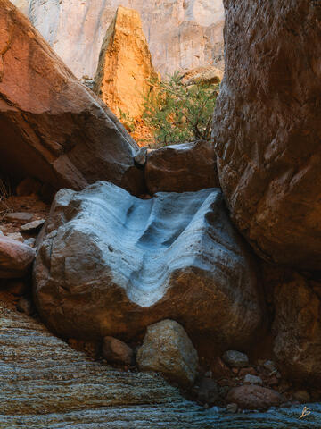 A pinnacle glows orange in the reflected light of the sun deep in a canyon within the Grand Canyon.