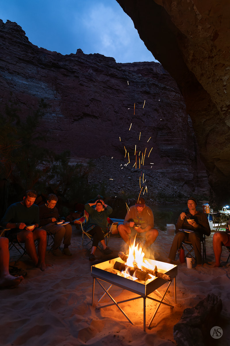 A group of river runners gather around the campfire while eating dinner at Little Redwall camp in Grand Canyon National Park.