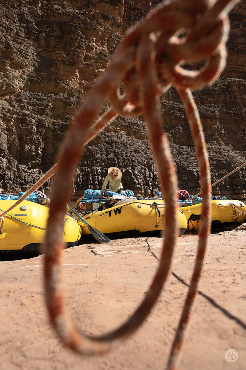 Looking thru a loop in a bowline as a man works on a raft in the Grand Canyon.