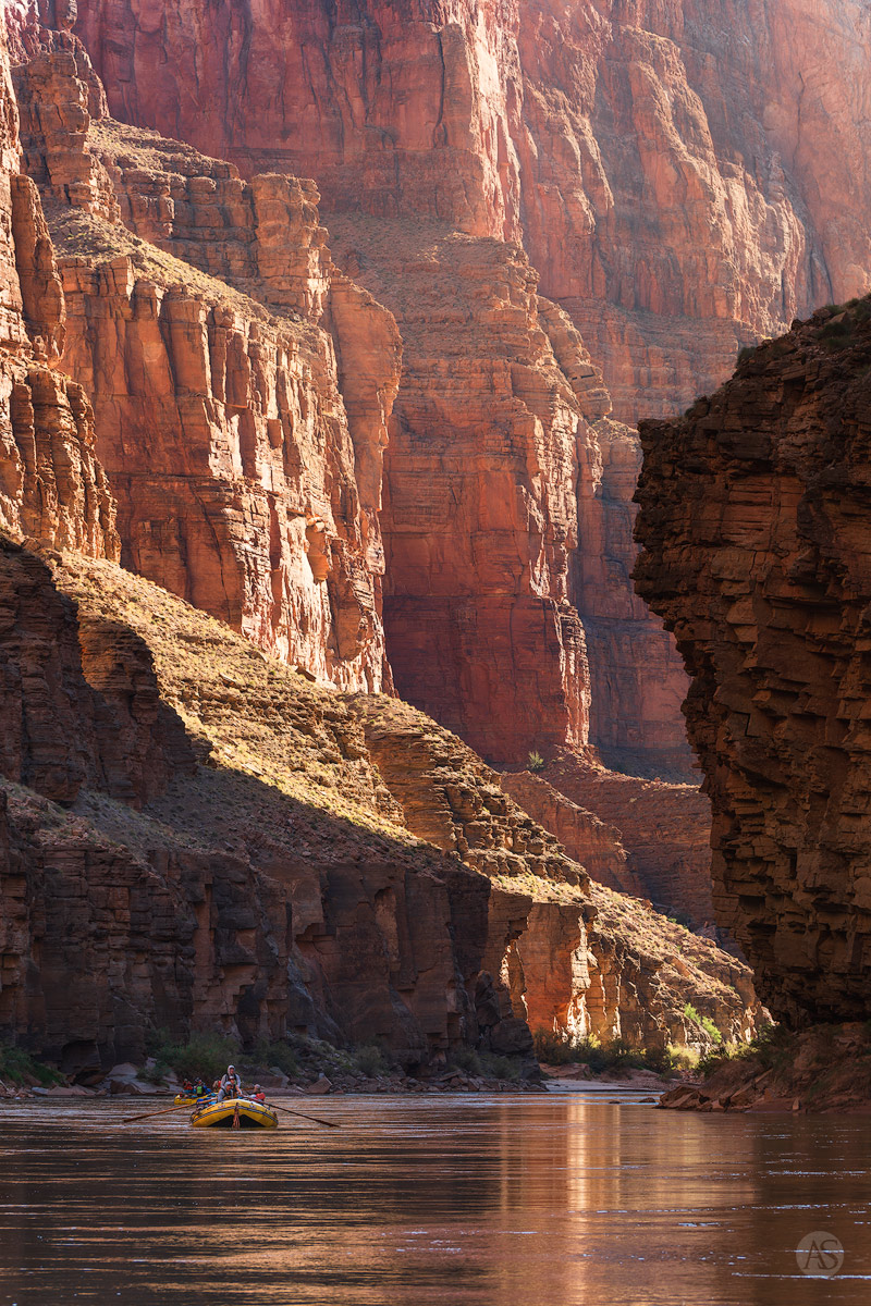 A yellow raft gracefully floats the Colorado River in the Grand Canyon.