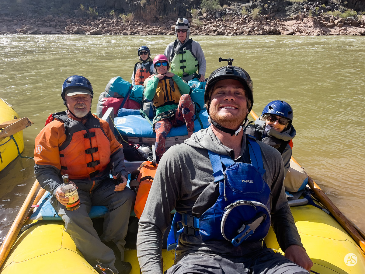 People wearing helmets on a yellow raft enjoy the experience of rafting the Colorado River in the Grand Canyon.