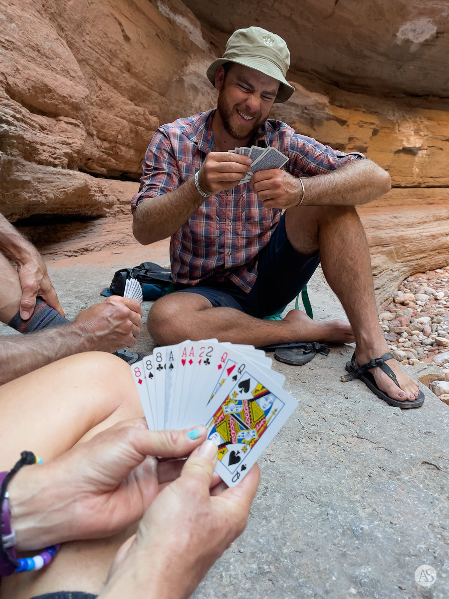 River guides sitting on rocks playing cards in the Grand Canyon.
