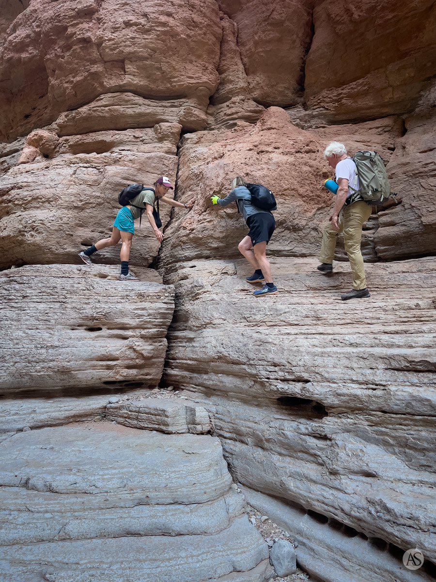 A river guide helps hikers on a cliff face in the Grand Canyon.