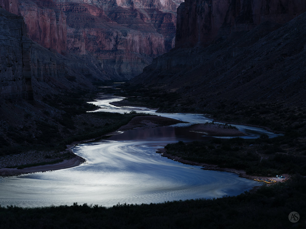 A moonlit view of the Colorado River and yellow rafts in the Grand Canyon.