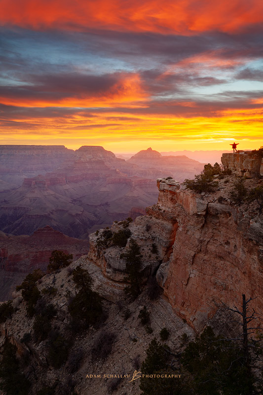 A person watches a colorful sunrise over the Grand Canyon